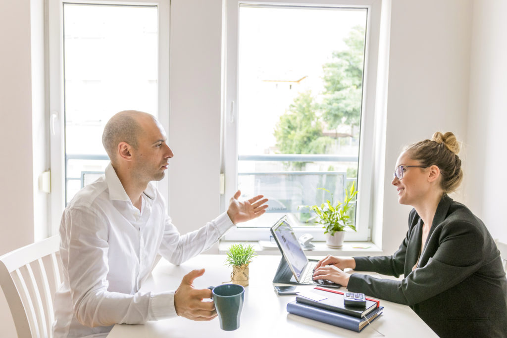 two-businesspeople-having-conversation-office