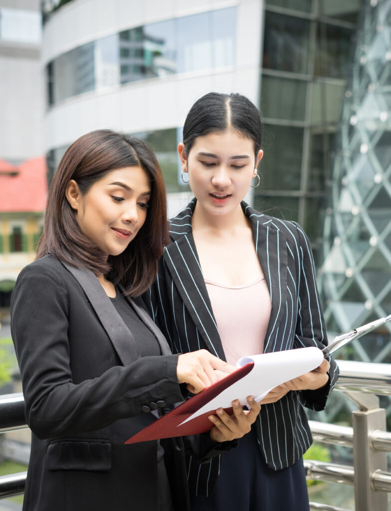 close-up-two-business-woman-looking-with-paper-document-together-while-walking-office-business-people-concept