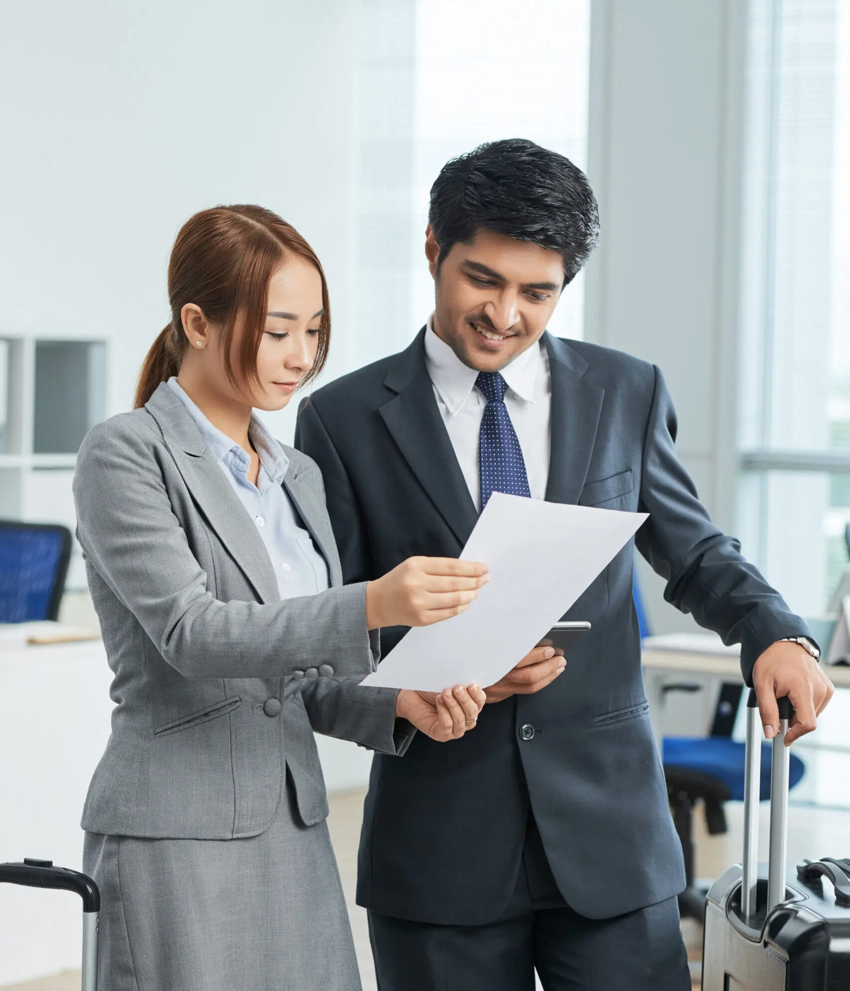 man-woman-business-suits-standing-office-with-suitcases-looking-together-document